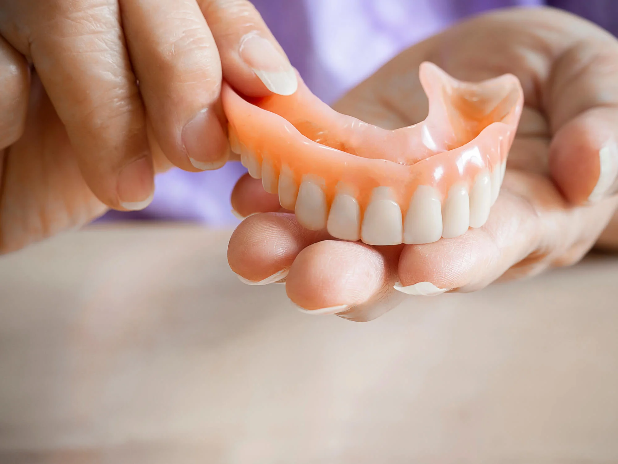 Senior Woman Holding Dentures In Canton, Michigan.