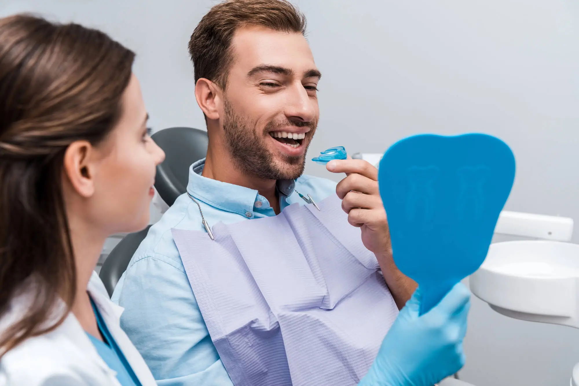 Selective Focus Of Happy Man Looking At Mirror And Holding Retainer Near Woman After A Full Mouth Re